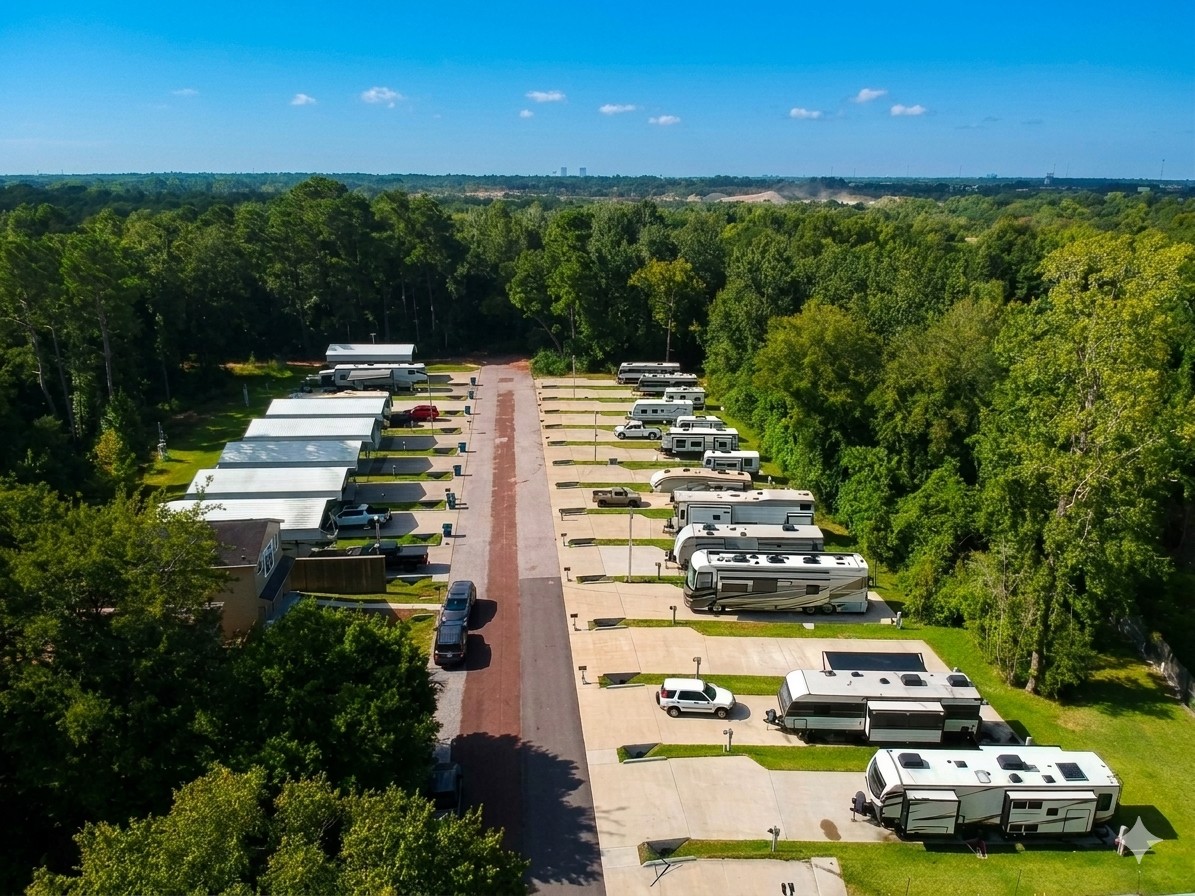 Aerial view of The Woodland RV Park, surrounded by dense green woods and clear blue sky